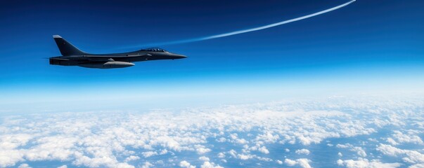 Naklejka premium A majestic fighter jet soaring through a clear blue sky, leaving a vapor trail behind as it navigates above fluffy white clouds.
