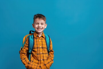 Portrait of smiling schoolboy with school bag isolated on light blue background