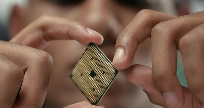 Young engineer in a office, holds in hand and checks the microprocessor, electronic chip close-up.