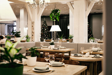 Christmas light modern interior of the restaurant with greenery with pleasant cozy lighting and...