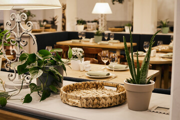 Christmas light modern interior of the restaurant with greenery with pleasant cozy lighting and festive table setting with glasses.