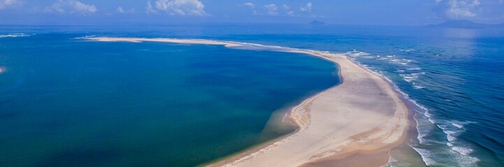Aerial view of a pristine sandy beach and azure ocean on a sunny day, perfect for summer vacations