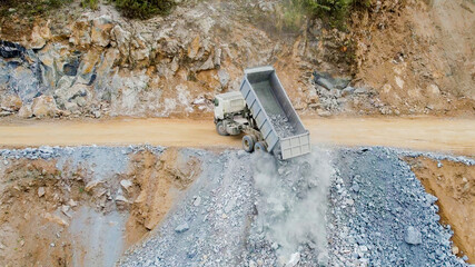 A large dump truck offloading gravel at a quarry site, illustrating the concept of industrial...