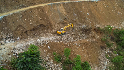 Excavator clearing a landslide on a mountainside, representing disaster management and construction...