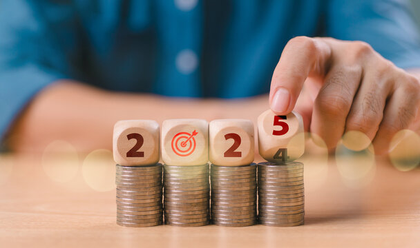 New Year 2025, budget plan concept. Businessman hand-flipped wooden block cube from end 2024 to start 2025 on coin stack, setup tax objective. Target and goal business cost. Money financial management