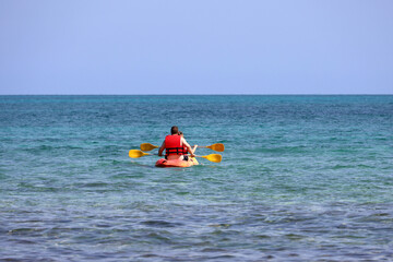 Kayaking in the sea, couple wearing life vests rowing with paddles in canoe. Man and woman in one team, travel and water sports