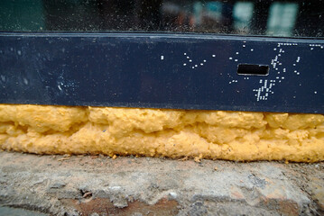 Polyurethane foam sealant applied to window seams closeup, installation process of sealing gaps and...