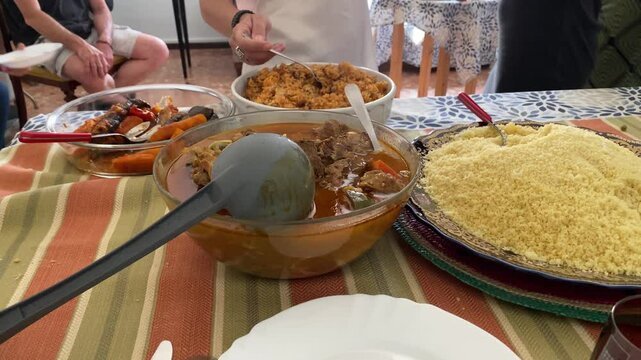 People serving themselves traditional couscous with vegetables and meat