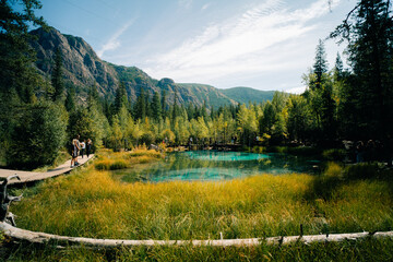 Blue geyser lake in autumn forest after snowfall. Altai, Siberia, Russia. Beautiful autumn landscape