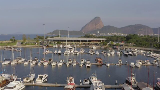 Sunlit aerial approach of Sugarloaf mountain in Rio de Janeiro over sailing boats in the gloria Marina / Marina da Gloria