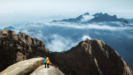 Bukhansan National Park, Seoul, South Korea - March 6, 2016: High angle and morning view of two female hikers on rock with the background of mountain peaks and sea of clouds