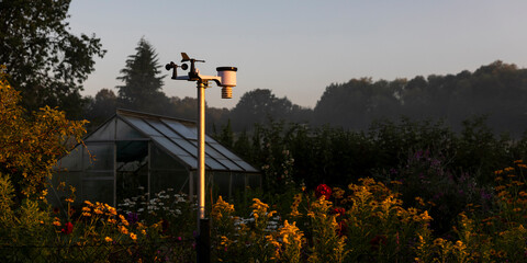 Private Wetterstation in einem Garten mit Gewächshaus bei Sonnenaufgang