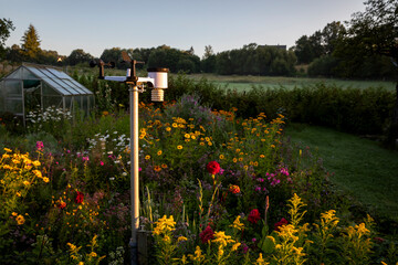 Private Wetterstation in einem Garten mit Gewächshaus bei Sonnenaufgang