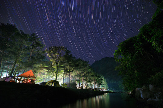 Galcheon-ri, Yangyang-gun, Gangwon-do, South Korea - August 10, 2016: Night view of tents for camping under pine forest besides Galcheon River against star light trajactory on sky