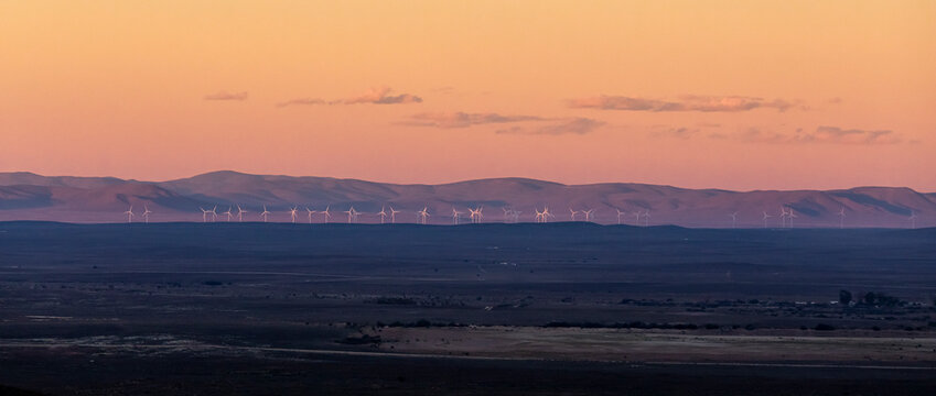View of wind farm at sunset with wind turbines and majestic mountains in the background, Tankwa Karoo, South Africa.