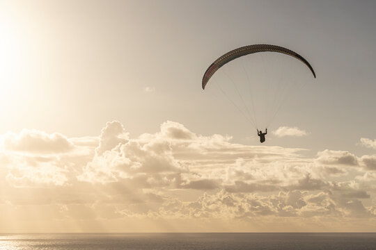 View of a beautiful sunset with a silhouetted paraglider over the ocean and clouds, Cape Town, South Africa.