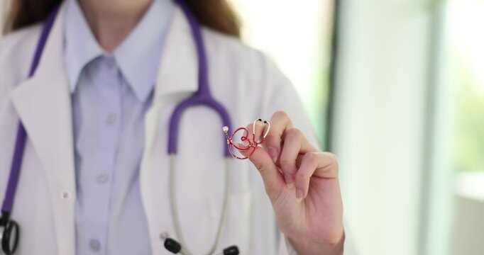 Female doctor displays heart-shaped brooch featuring stethoscope. Accessory represents commitment to medical field and passion for heart health
