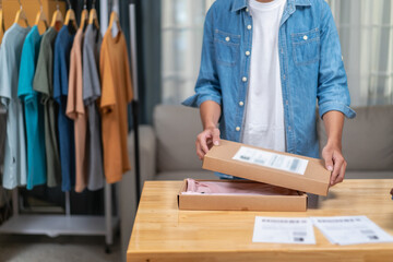 Young Asian man, distributor, online shop owner, small business owner, standing in warehouse and preparing to ship goods, with parcel boxes.