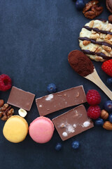 Macarons, chocolate, cookies, berries and various nuts on dark blue background. Top view.