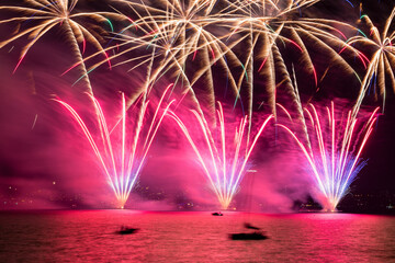 View of colorful fireworks exploding over Lake Zurich with vibrant reflections in the water, Zurich, Switzerland.