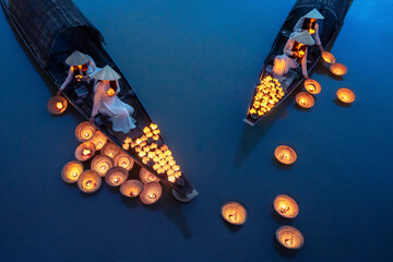 View of peaceful lanterns floating on a tranquil river at dawn with Vietnamese ladies in ao dai, Hue, Vietnam.
