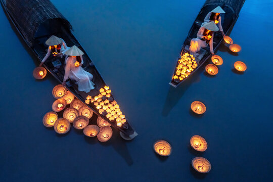 View of peaceful lanterns floating on a tranquil river at dawn with Vietnamese ladies in ao dai, Hue, Vietnam.