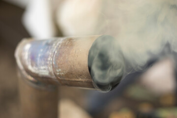 Fototapeta premium Smoke from a steel pipe. Hot pipe. Smoke from a samovar.