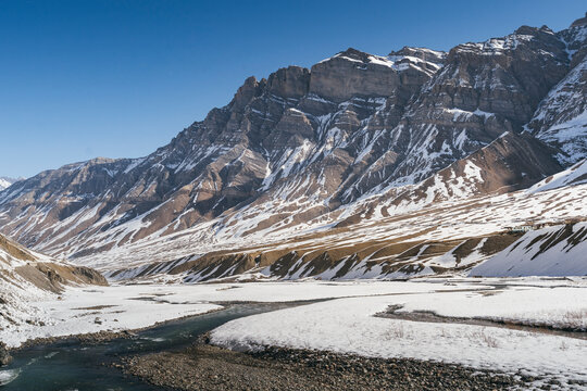 View of snow mountains and frozen rivers with picturesque villages in a serene landscape, Pin Parvati Valley, Kaza, Spiti Valley, India.