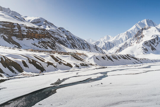 View of snow mountains and frozen rivers in winter with picturesque villages, Pin Parvati Valley, Kaza, Spiti Valley, India.