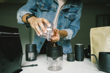 Coffee preparation, people pouring coffee powder using Automatic grinder ground coffee beans, light roast Arabica, maker coffee at home