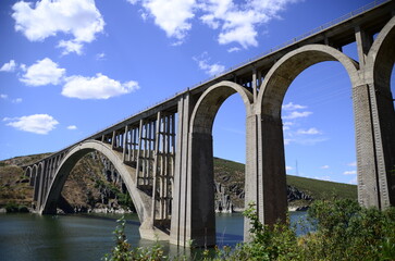 Very high stone bridge with many arches over the river.