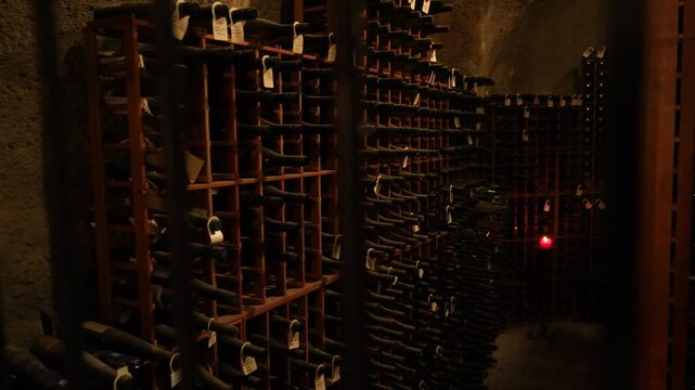 Vintage wine bottles stacked in old winery cellar rack for aging.