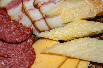 Sliced ​​cheese, sausage and lard on a plate.