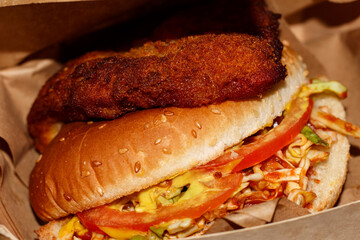 Burger with a cutlet on top of a bun. Juicy schnitzburger on the table.