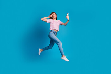 Obraz premium Full body photo of attractive young woman runner v-sign selfie photo dressed stylish striped pink clothes isolated on blue color background