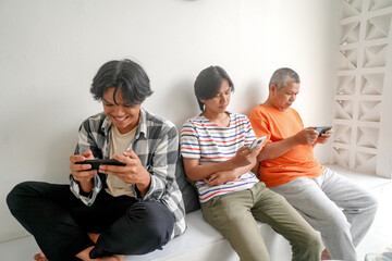 Asian Father And His Two Son Using Mobile Phone Playing Games Together