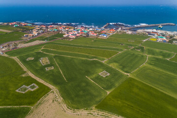 Aerial and spring view of green barley field and red house loofs besides sea at Gapado Island near Seogwipo-si, Jeju-do, South Korea 