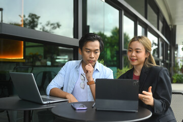 Smiling female financial advisor consulting client and reviewing financial data on digital tablet