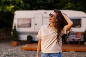 Happy young woman sitting with in front of her camper van during a trip