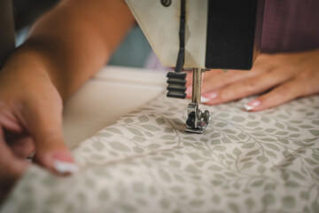 Close up on hands of unknown woman sewing on electric sewing machine