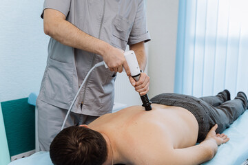 Shockwave therapy session for back pain relief in a clinical setting with a professional therapist