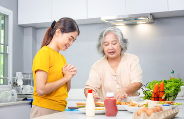 Senior asian mother and middle aged daughter cooking together at kitchen