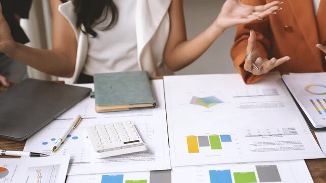 Strategic Financial Collaboration: Two businesswomen analyze charts and graphs, engaging in a lively discussion to drive data-driven decisions for business growth and success. 