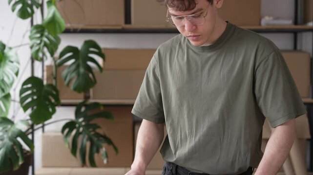 Young attractive hipster man packing product small business parcel order online retail store for delivery to customer. 