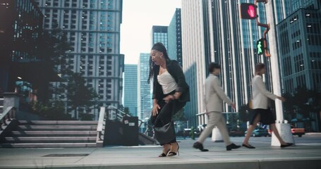 Cheerful Black Female in a Business Suit Performing a Happy Dance on a Busy Street Sidewalk with Concrete Buildings. African Female Celebrating a Promotion, Business Partnership or an Investment 