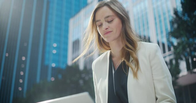 Portrait of a Cheerful Businesswoman Sitting in a Park in a Modern Urban Plaza, Typing on Her Laptop Computer. Manager is Responding to Urgent Emails and Managing Her Project Deadlines