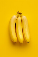 Three yellow bananas are sitting on a yellow background