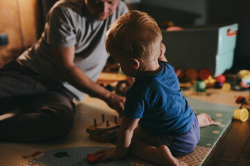 Little boy with his dad playing with toys at home. Happy father and son spending time together