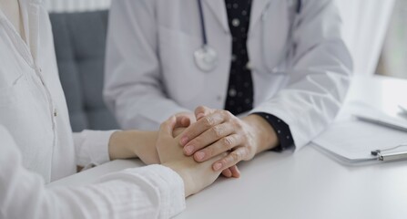 Doctor and a patient. The female physician, wearing a white medical coat over a dark blue dotted blouse, is reassuring a woman during a consultation in the clinic. Medicine concept