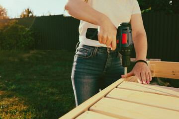 Female carpenter at work using hand drilling machine. Woman using an drilling tool on wood in a home renovation project